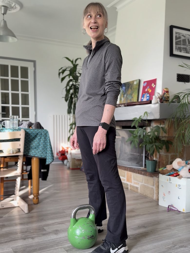Une cliente de La Forge dans son salon, kettlebell à ses pieds